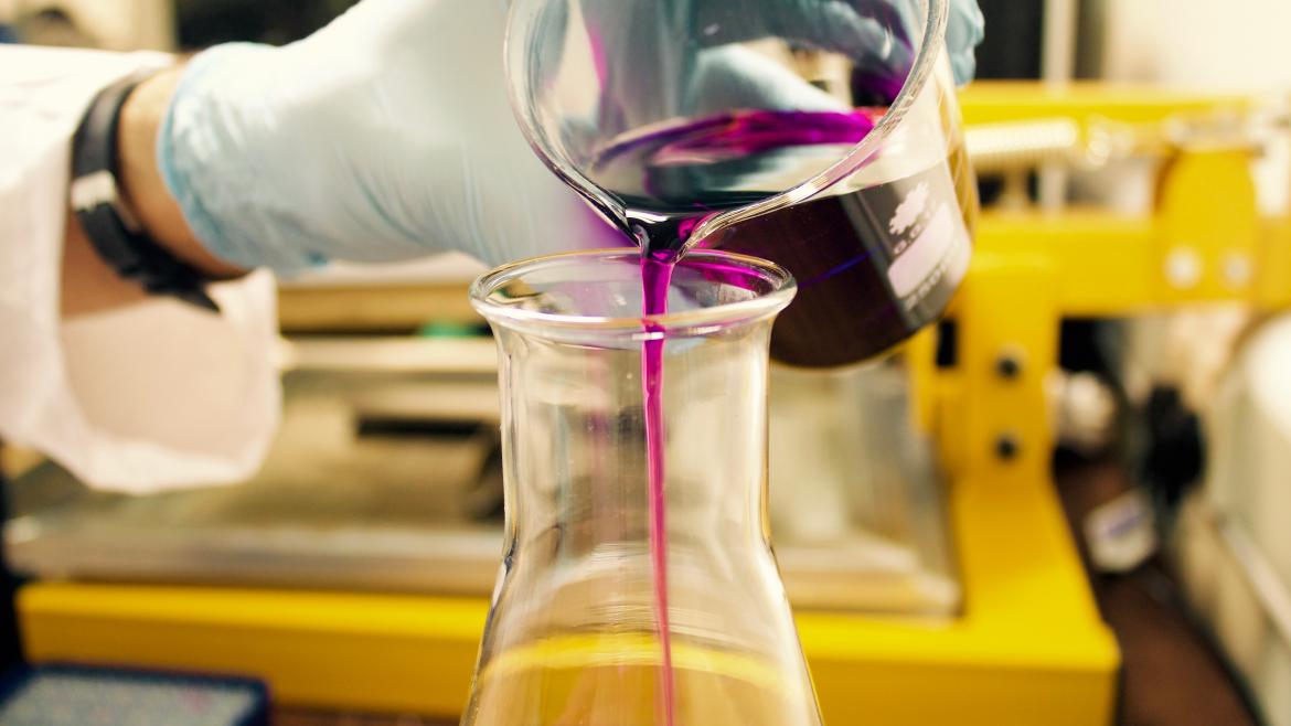purple liquid being poured into a flask